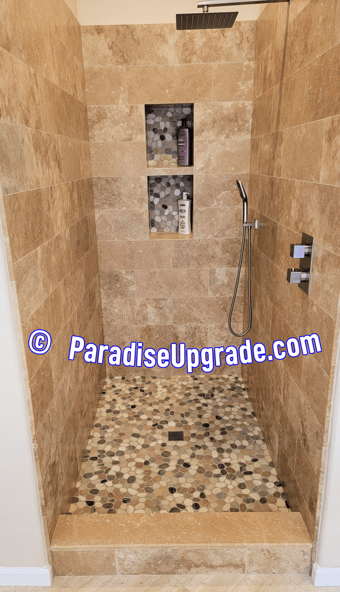 Shower tile installation in Anthem, AZ 85086. Wall tile is 8"x20" travertine with pebble tile on shower floor. Rain/waterfall shower head and hand-held sprayer. Easy-reach faucet from outside the shower.