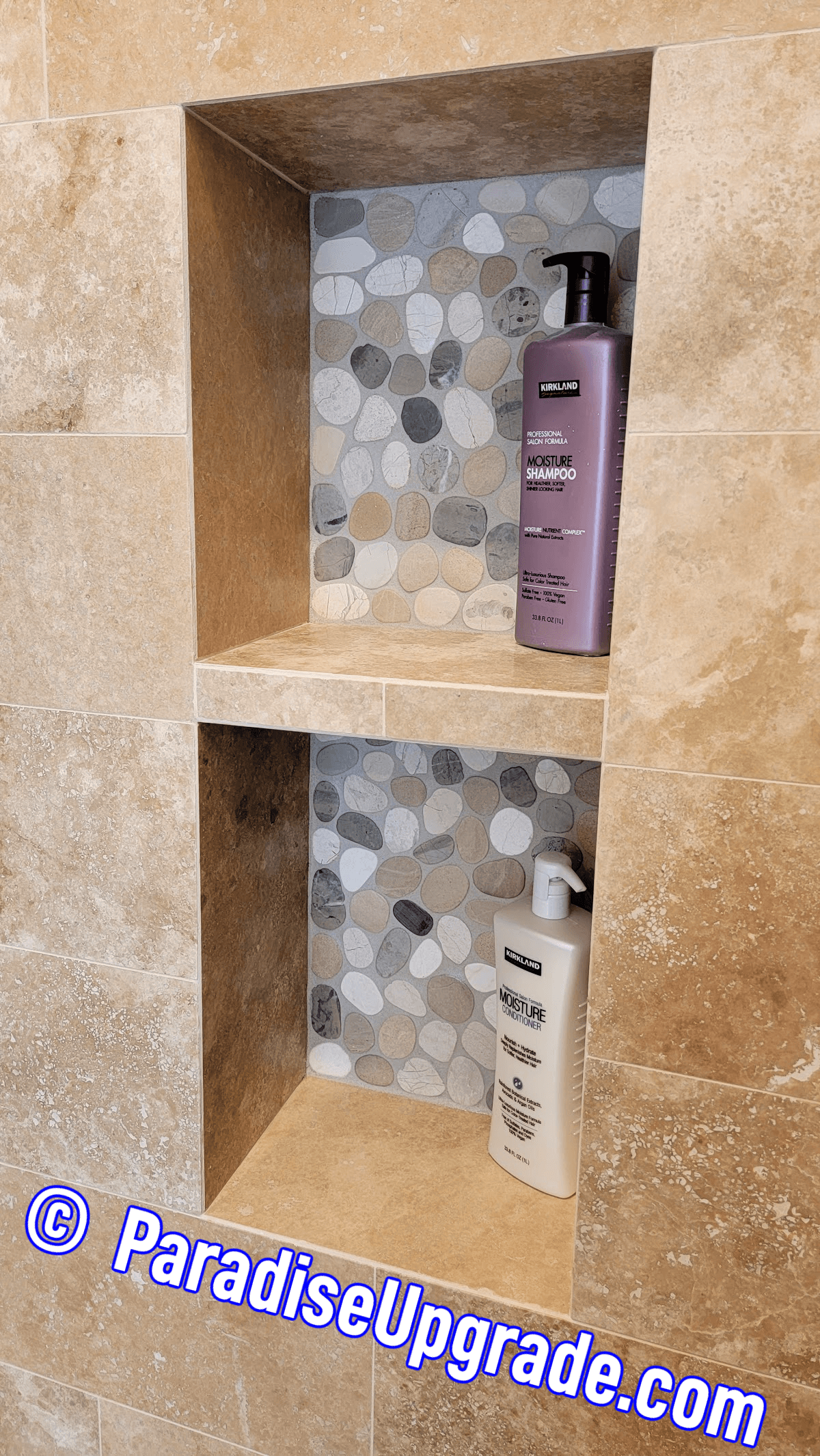 Anthem custom shower niche made with travertine tile including a travertine shelf. The back of the niche has pebble tile and epoxy grout to match the shower floor. Installation by Paradise Upgrade